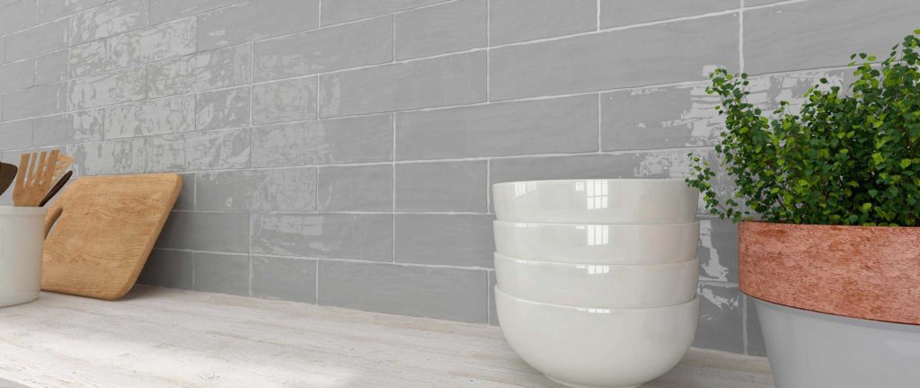 A custom natural cut on a smoky high gloss gray subway tile. Available at Custom Home Interiors